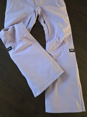 Dope Con, skidbyxa stl S - Lila skidbyxor från Dope, modell Con i stl Small. Lätt vadderade. Fint skick men slitna nedtill av pjäxorna se bilder på fram och baksida. Inget som påverkar funktionen eller syns när man har dem på sig. 