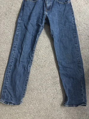 Blå raka jeans i klassisk modell från Levi’s i storlek w31 L30 - Ett par blå jeans med rak passform och fem fickor. Jeansen har en klassisk midja och är gjorda i denim med synliga sömmar. Perfekta för en avslappnad stil och passar till det mesta 