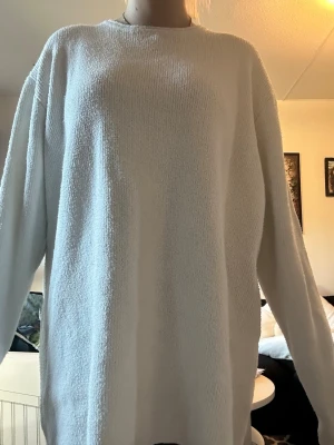 Oversized vit stickad tröja - Enkel och stilren vit stickad tröja med rund hals och lång ärm. Tröjan har en oversized passform och är perfekt för lager-på-lager. Mjuk och skön känsla, passar till många olika outfits.