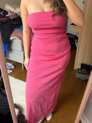 Rosa axelbandslös långklänning - Säljer denna rosa bandeuklänningen med slit på sidorna och scrunch som formar midjan. Endast använd en gång!💕