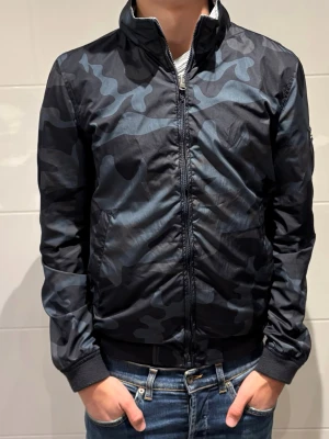 Woolrich jacka - Säljer denna Woolrich jacka i kamouflage men går också att vända ut och in för en grå färg | Extremt populära och eftertraktade då de inte finns att köpa nya längre! | Skick 9,5/10 | Vårt pris=999kr | Hör av dig vid minsta fundering 