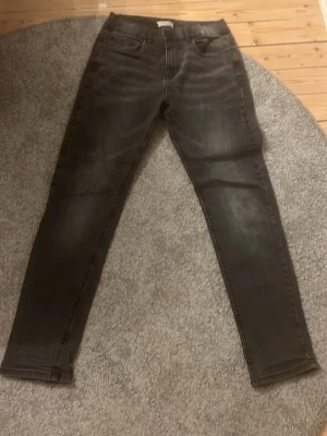 Svarta skinny jeans med stretch - Säljer ett par svarta skinny jeans med stretch och klassisk femficksmodell. Jeansen har en något tvättad look och smala ben. Perfekta för dig som gillar en tajt passform och enkel stil.