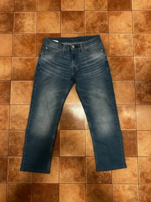 Levis  - Säljer ett par blå jeans med raka ben och snygga slitningar på låren och knäna. Byxan är i L32 men har sytt ner dem till L30