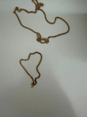 Edblad 14K guldpläterat kedjeset – Armband (20 cm) & 50 cm halsband | Vattentåligt & nickelsäkert - Uppgradera din smyckessamling med detta tidlösa kedjeset från Edblad med matchande armband och halsband i en stilren, klassisk design. Bär dem tillsammans för en polerad och självsäker look. Bär dem var för sig för en perfekt touch av avslappnad lyx. Helt oanvänt, endast provat.  Tillverkat i blank 14K guldplätering på slitstarkt rostfritt stål – gjort för att bäras varje dag. Setet är vattentåligt, nickelsäkert och designat för att behålla sin vackra glans över tid. Stilrent, praktiskt och enke