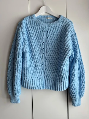 Ljusblå supermjuk stickad tröja. S. H&M. - Mysig supermjuk ljusblå  tröja med breda ribbade muddar vid ärmslut och nederkant. Ballongärmar. Tröjan har rund halsringning och ett dekorativt hålmönster framtill. Storlek S. Från H&M. Perfekt för dig som gillar oversized och trendig stil. Tror inte den är använd. Finns inget att anmärka på. Nyskick. NWOT. 