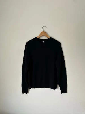 Svart stickad tröja från Uniqlo - En stilren svart stickad tröja från Uniqlo med rund halsringning och långa ärmar. Tröjan har en enkel och klassisk design som passar till det mesta. Perfekt för lager på lager och enkel att matcha med olika outfits. 8B5