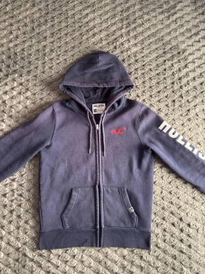 Hollister zip hoodie  - Tja, säljer denna feta Hollister zip hoodien i mycket bra skick. Storleken är XS och passar perfekt för dig som är mellan 168-173 cm lång! Modellen på bilden är 170, 57kg. Mitt pris är 499, men kan diskuteras vid snabb affär! Den enda defekten på hoodien är att den är lite urtvättad men inte alls så mycket på bilden då solen låg på när jag tog bilden. Hör av er vid frågor eller minsta fundering! 