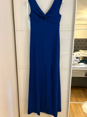 Marinblå långklänning med v-ringning - Snygg marinblå långklänning med djup v-ringning och twistad detalj framtill. Klänningen är ärmlös och har en slits framtill som ger en elegant look. Perfekt för dig som vill sticka ut med en klassisk och stilren klänning. Använt en gång original pris 999kr (bilderna längst bort är från Zalando)