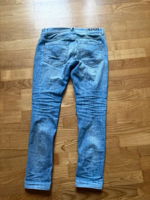 Ljusblå raka jeans från dondup - Säljer ett par ljusblå jeans från JC med klassisk femficksdesign och raka ben. Jeansen har snygga slitningar och kontrastsömmar, perfekta för en avslappnad stil. Materialet är mjukt denim i bomull som ger en skön känsla hela dagen.