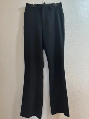 Svarta kostymbyxor från Bik Bok - Snygga svarta kostymbyxor från Bik Bok med raka ben och klassisk passform. Byxorna har hysk- och hakstängning samt dragkedja framtill. Tillverkade i ett mjukt tyg med lätt glansig finish och diskret struktur. Perfekta för en clean och stilren look. Obs, saknas en knapp men funkar lika bra. Pris kan diskuteras ❤️