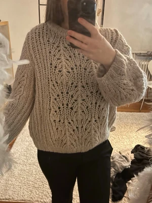 Beige  stickad tröja - Säljer en beige chunky stickad tröja med grovt hålmönster och breda ärmar. Tröjan har en avslappnad passform och ribbstickade muddar vid ärmslut och nederkant. Perfekt för lager på lager och riktigt mysig till hösten och vintern.
