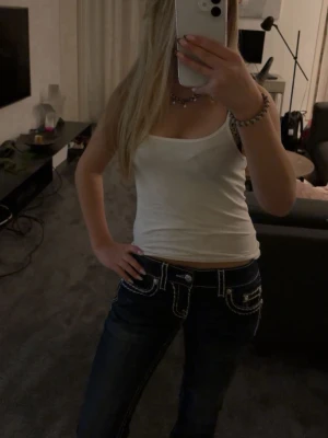 Mörkblå Miss me jeans - Säljer ett par mörkblå lågmidjade bootcut jeans från Miss me med tydliga vita kontrastsömmar och dekorativa fickor bak. 