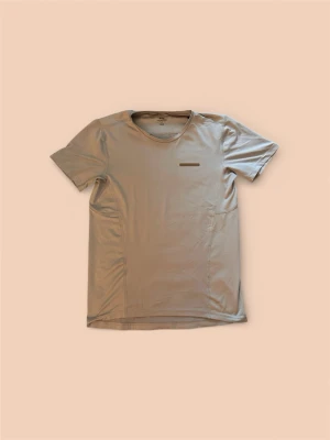Beige sport-tshirt med meshdetaljer från Zlatan - Snygg beige sport-tshirt från zlatan  med rund hals och korta ärmar. Tillverkad i ett lätt och snabbtorkande material med ventilerande meshpaneler under ärmarna för extra komfort under träning. Perfekt för gymmet eller löprundan.