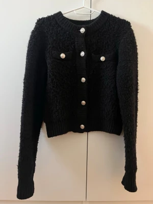 Kofta - Svart kofta från H&M med guldiga knappar. Fint skick men är lite ”nopprig” i materialet.. 