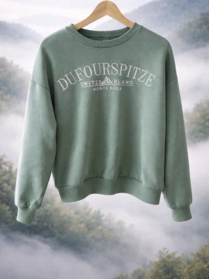 Grön sweatshirt Dufourspitze - Mysig grön sweatshirt med trycket 'DUFOURSPITZE SWITZERLAND MONTE ROSA' framtill. Tröjan har rund halsringning, ribbade muddar vid ärmslut och nederkant samt mjukt fleecefoder på insidan. Perfekt för en avslappnad och trendig look.