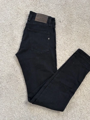 Svarta replay jeans - Snygga svarta jeans med rak passform och klassisk femficksdesign. Jeansen har normal midja och är tillverkade i ett stretchigt denimtyg som ger en bekväm känsla. Perfekta för en stilren och enkel look.