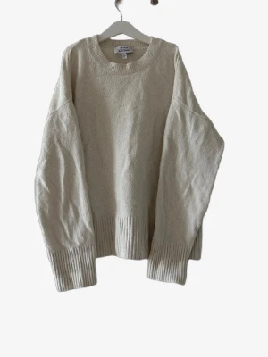Beige stickad tröja från & Other Stories - Oversized beige stickad tröja från Arket med rund halsringning och breda ribbade muddar vid ärmslut och nederkant. Tröjan har en enkel och clean design, perfekt för lager på lager och chill stil. Materialet ser ut att vara mjukt och skönt.