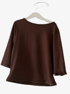 Brun långärmad topp 🌸 - Mörkbrun långärmad topp med enkel och avslappnad passform. Tillverkad i mjuk bomull och har en rund halsringning samt trekvartsärm. Perfekt att styla med jeans eller kjol för en clean look.