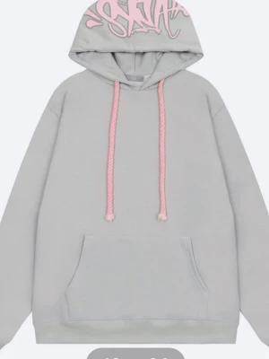 Syna world - Snygg ljusgrå hoodie med rosa snören och graffiti-inspirerat tryck på huvan. Hoodien har en klassisk känguruficka framtill och ribbade muddar vid ärmar och nederkant. Perfekt för en chill och avslappnad stil. Materialet ser ut att vara mjuk bomullsblandning.