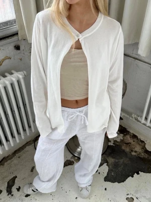 Design by si topp - Trendig design by si topp, använd 1 gång! Snygg vit cardigan med en enkel knapp vid halsen och öppen framtill. Långärmad och i mjukt, tunt material som ger en avslappnad och fräsch look. Perfekt att slänga över ett linne eller t-shirt för en stilren vibe.🥰