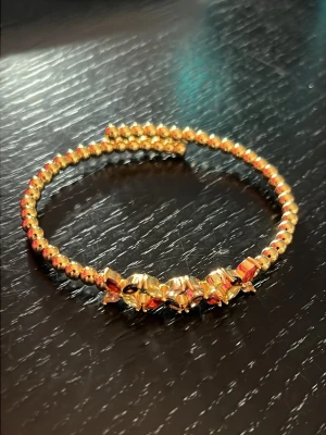 U.S Polo armband med kristaller - Snyggt halsband med guldfärgade pärlor och glittriga detaljer i rött, svart och gult framtill. Halsbandet har en rund form och pärlorna ger en lyxig känsla. Perfekt för dig som vill sticka ut med accessoarerna.