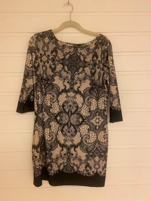 Mönstrad klänning från Primark - Säljer en snygg kortklänning från Primark med svart och beige mönster. Klänningen har trekvartsärm och rund halsringning. Materialet är mjukt och stretchigt, perfekt för dig som gillar bekväma men stilrena plagg.
