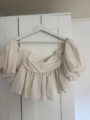 Vit offshoulder topp med puffärmar - Supersöt vit offshoulder topp från H&M med stora puffärmar och croppad passform. Toppen har en romantisk vibe med rynkade detaljer och elastisk smock i ryggen. Perfekt för dig som vill sticka ut med en trendig och luftig look.