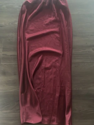 Vinröd långkjol från Missay - Säljer en vinröd långkjol från Missay med elastisk midja. Kjolen är i satin. Aldrig använd