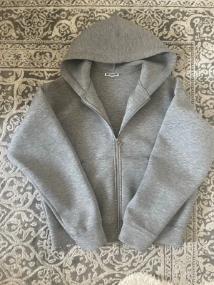 Scuba Weekday - Nypris : 600 kr                                                         Mitt pris : 449 kr                                                   Säljer en stilren grå hoodie från Weekday med dragkedja framtill och stor huva. Hoodien har en relaxed fit och är gjord i mjukt sweatshirtmaterial. Perfekt för en chill och avslappnad look.