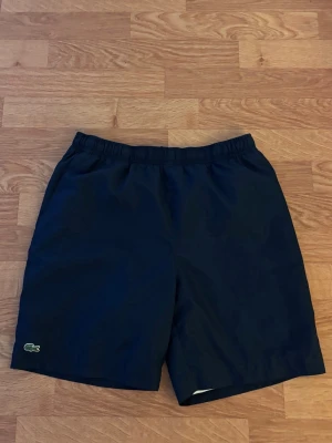 Lacoste shorts - Ett par feta Lacoste shorts med färgen marinblå. De är luftiga och mysiga, perfekt nu till sommaren/hösten. Priset är ej hugget i sten. Skriv vid frågor!🤗