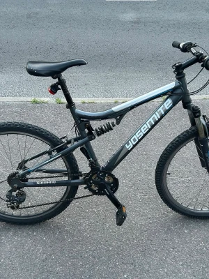Svart Yosemite mountainbike - Säljer en svart mountainbike från Yosemite med Shimano-växlar och dämpad ram. Cykeln har robusta däck, sportig design och bekvämt sadel. Perfekt för dig som gillar att cykla i terräng eller på asfalt.