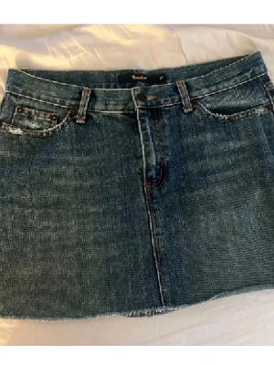 Blå jeanskjol från Crocker - Säljer en klassisk blå jeanskjol från Crocker i kort modell. Kjolen har fem fickor, bälteshällor och rå kant nedtill för en avslappnad look. Perfekt till vardags och enkel att matcha med olika toppar.