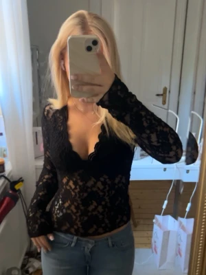 Svart spetstopp med v-ringning - Super snygg svart långärmad blus i spets med v-ringning från Gina Tricot använd 2 gånger. Storlek S 