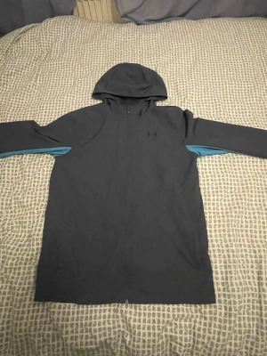Mörkblå vindjacka från Under Armour - En skön mörkblå vindjacka inför våren samt sommaren när det är en regnig dag som sker väldig mycket här i Sverige.       Jag säljer den eftersom den är för stor för mig och den passar mig inte den är så storlek YXL som är storlek S 