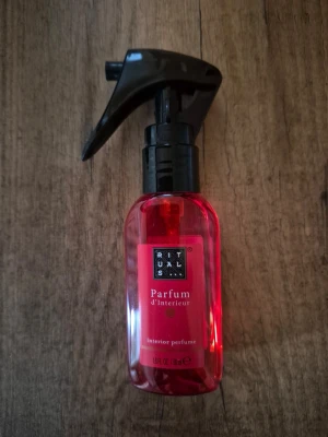 Rituals Parfum d’Interieur rumspray - En stilren röd sprayflaska från Rituals med svart munstycke. Flaskan är gjord av plast och innehåller Parfum d’Interieur, en inredningsparfym som ger rummet en fräsch och exklusiv doft. Perfekt för dig som vill ha en lyxig känsla hemma.