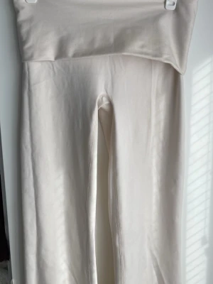 Vita yogapants, lågmidjade, träningskläder  - Säljer ett par vita yogapants med låg midja. De är utsvängda. Skicket är helt nytt, inga fläckar!! Jättebra till träning eller till vardag. Träningsmatrial  storlek xs 