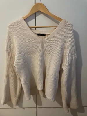 Beige stickad tröja Gina Tricot - Säljer en beige stickad tröja från Gina Tricot med v-ringning och vida ärmar. Tröjan har en avslappnad passform och är ribbstickad i mjukt material. Perfekt för lager på lager och enkel att styla till olika outfits. Lite smink vid halsringningen annars super skick 