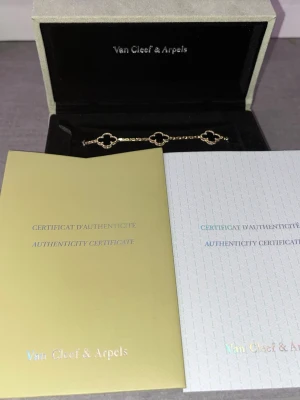 Van Cleef & Arpels Alhambra armband - Exklusivt armband från Van Cleef & Arpels med tre ikoniska Alhambra-klöver i svart och guldfärgad metall. Kedjan är tunn och elegant, perfekt för att ge en lyxig touch till din stil. Levereras i originalask med äkthetsintyg.