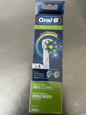 Oral-B Cross Action borsthuvuden - Förpackning med tre Oral-B Cross Action borsthuvuden med CleanMaximiser-teknologi. Borsthuvudena har gröna och vita borststrån och är designade för att ta bort mer plack och ge helhetsrengöring. Passar elektriska tandborstar från Oral-B och är designade av Braun.