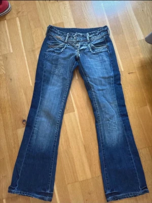 Lågmidjade bootcut jeans - Snygga Lågmidjade utsvängda jeans med sliten stil! Använda vid ett tillfälle så nytt skick! W25 och smått långa på mig som är 160😚