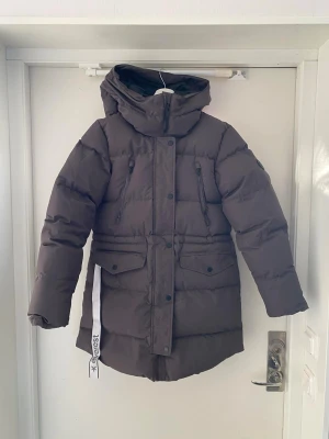 Vinterjacka från Everest - Vinterjacka från Everest med huva (Modell: W Warm Parka) i färgen Plum Slate. Fyra fickor framtill och även en innerficka. Kan dras åt i midjan. Jackan är i nyskick och använd fåtal gånger, säljes pågrund av för liten storlek. Storlek 36 (liten i storlek). Nypris 1499kr