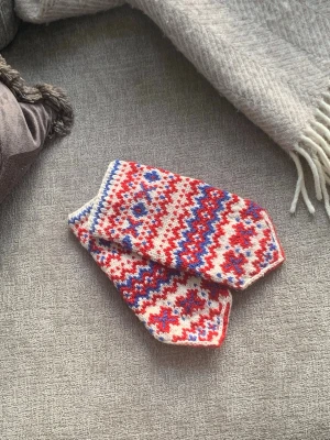 Stickade vantar med rött och blått mönster - Unika stickade vantar med traditionellt mönster i rött, blått och vitt. Vantarna har spetsig topp och tumme, perfekt för kalla dagar. De är handgjorda i mjukt ullgarn och har en riktigt mysig känsla.