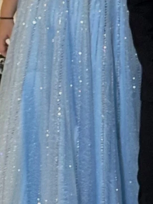 Ljusblå glittrig långklänning - Magisk ljusblå långklänning med glittriga detaljer som fångar ljuset. Klänningen har en svepande siluett och är perfekt för speciella tillfällen. Materialet känns lätt och elegant, vilket ger en drömmig känsla.snörkorset på ryggen som gör att den passar dem fläska storlekarna, perfekt till skol balen, bröllop, förlovning mm., ärmarna är sydda i efterhand och kan tas bort lätt om man vill ha bara banden. Fler bilder kan skickas