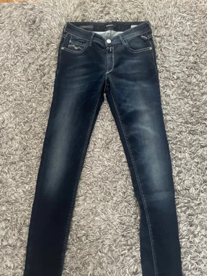 Mörkblå super skinny jeans Replay - Säljer ett par mörkblå super skinny jeans från Replay. Jeansen har klassisk femficksdesign, snygga slitningar och kontrastsömmar. Materialet är stretchigt för en tight passform och de har en låg midja. Perfekta för dig som gillar en slimmad look.
