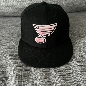 Svart keps med rosa NHL-logga - Snygg svart keps med rosa St. Louis Blues-logga framtill och liten rosa NHL logga bak. Säljer då den tyvärr var för liten, hör av er vid frågor. Strl 7