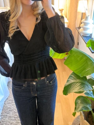 Svart topp med volang - Snygg svart omlottopp från Gina Tricot med markerad midja och volang nedtill. Med lite glitter 💕