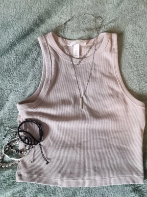 Grunge ribbad topp - Beige linnetopp från H&M. Toppen är ribbad och ärmlös med rund halsringning, perfekt för lager på lager eller att bära som den är. Använd fåtal gånger utan defekter. Bekväm och stretching, är bara inte min stil.