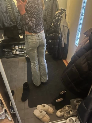 Ljusblå bootcut jeans - Säljer ett par ljusblå bootcut jeans med låg midja och klassiska fem fickor. Jeansen har en avslappnad passform och är perfekta för en trendig vardagslook. Materialet är denim i bomull.