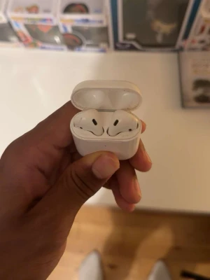 Apple AirPods - Säljer ett par trådlösa Apple AirPods med vitt laddningsetui. Hörlurarna har en stilren och minimalistisk design i blank vit plast. Perfekta för musik, poddar och samtal på språng. Laddningsetuiet är kompakt och smidigt att ta med sig överallt. Gamla ämvänder inte. Äkta.