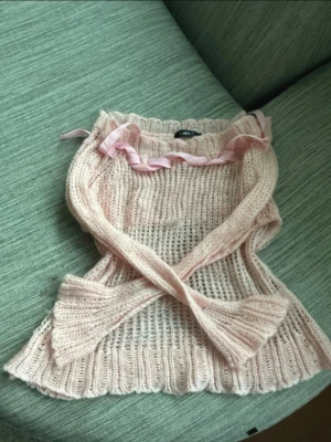 Ljusrosa stickad tröja med rosett -  Oversized. Supersöt ljusrosa stickad tröja från Salto med breda ribbstickade muddar och en dekorativ rosett i satinband vid halsen. 